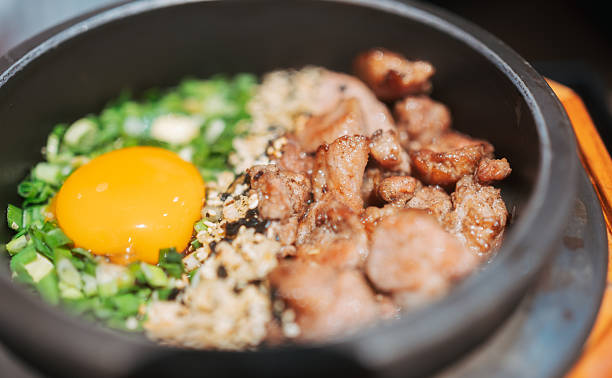 korean bibimbap with egg and grilled meat in hot stone bowl