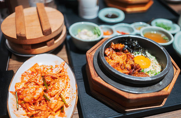 hot stone bowl rice dish being mixed with spoon in korean style presentation, sizzling comfort food captured in close-up restaurant dining environment
