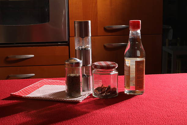 Kitchen table with seasoning jars and a bottle of vinegar ready for cooking