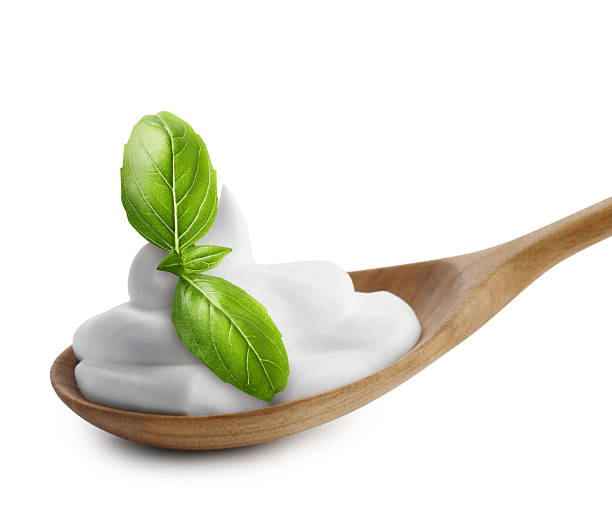 Spoon with delicious yogurt and basil isolated on white
