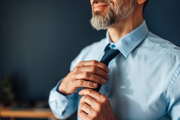 A close-up view of a man's hands adjusting his tie, symbolizing focus, dedication, and preparation in a professional environment.