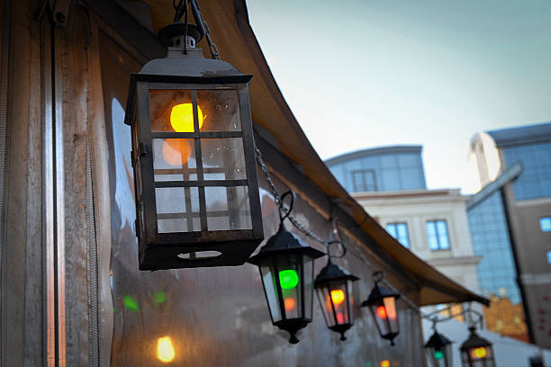 Row of hanging outdoor lanterns with warm colored lights creating an atmospheric evening street decoration.