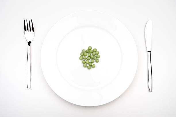 A spoonful of food is on a white plate. The food is a mix of vegetables, including carrots and peas