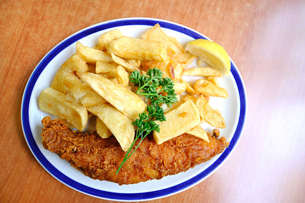 Studio shot of cod, chips and mushy peas with tartar sauce and a lemon garnish cut out against white background