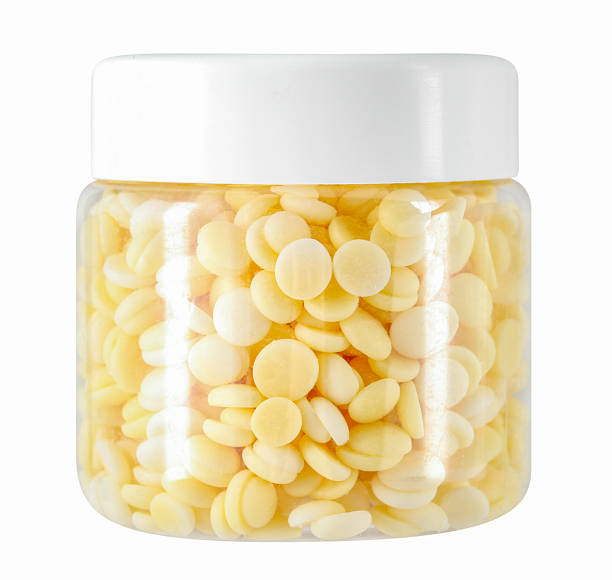 Plastic jar with closed lid, yellow colored cake icing sprinkles, cutout, studio shot, white background