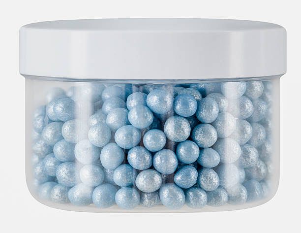 Plastic jar with closed lid, metallic blue colored cake icing sprinkles, cutout, studio shot, white background