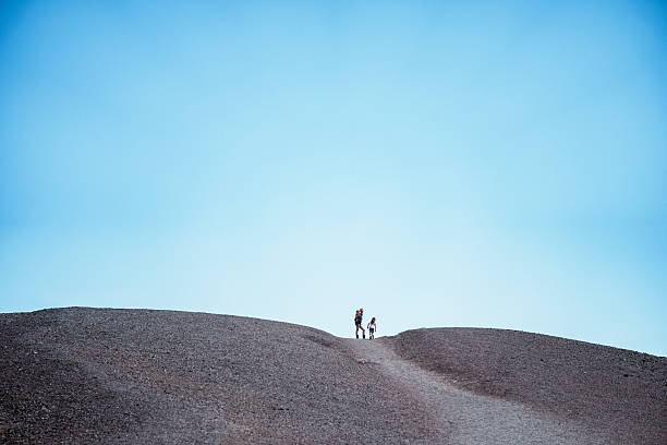 A mother and her children stand together at the top of a volcanic cinder cone during a summer road trip stop at Craters of the Moon National Monument in Idaho.