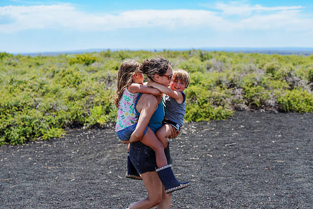 A Eurasian mother carries her two young children while exploring the summit of Inferno Cone at Craters of the Moon National Monument in Idaho on a summer afternoon.