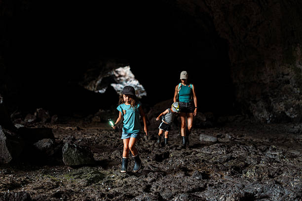 A five-year-old girl leads the way with a flashlight while hiking with her family through a lava tube cave at Craters of the Moon National Monument in Idaho.