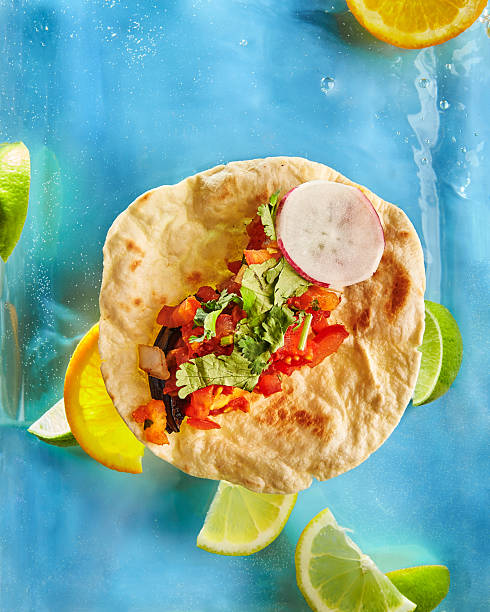 Tacos on corn tortillas with beef, chicken and vegetable fillings on white background with lime wedges