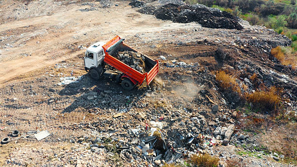 Dump truck emptying construction debris and garbage at an outdoor landfill site