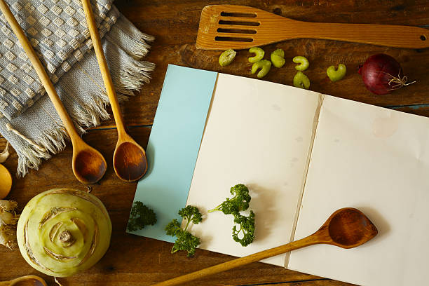 recipe book or cookbook with various vegetables and vintage kitchen utensils,free copy space on empty book page
