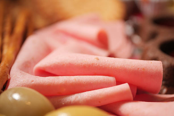 Thin slices of deli meat arranged with olives and snacks for serving.