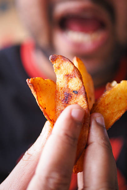 A person holds crispy potato slices in hand, ready to eat.