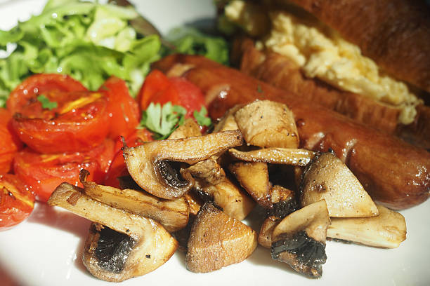 Mushrooms, tomatoes, scrambled eggs, and sausage are artfully arranged.