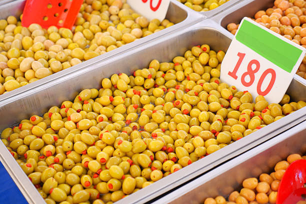 Fresh olives displayed in vibrant trays at a busy outdoor market.