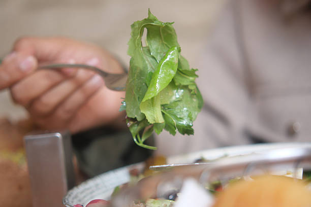 A person is enjoying a vibrant green salad at a table during lunch.