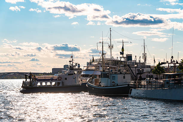 Boats are docked in stockholm harbor with sparkling water and a cloudy sky