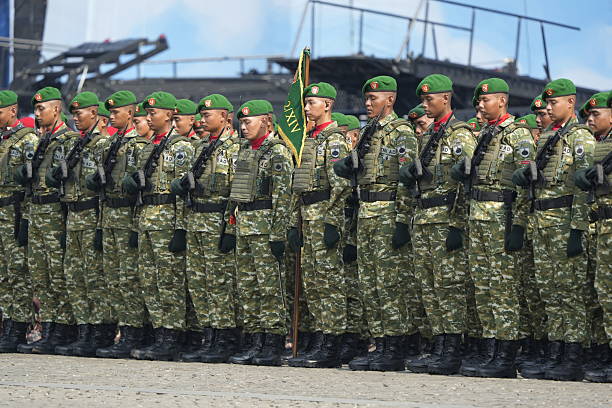 Jakarta, Indonesia -  October 5, 2025 : Indonesian National Armed Forces (TNI) personnel from various units participate in a military parade during the 80th anniversary celebration of the TNI at the National Monument (Monas) in Jakarta. Soldiers stand in formation with rifles while a military marching band performs during the official ceremony.