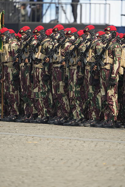 Jakarta, Indonesia -  October 5, 2025 : Indonesian National Armed Forces (TNI) personnel from various units participate in a military parade during the 80th anniversary celebration of the TNI at the National Monument (Monas) in Jakarta. Soldiers stand in formation with rifles while a military marching band performs during the official ceremony.