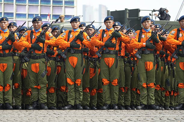 Jakarta, Indonesia -  October 5, 2025 : Indonesian National Armed Forces (TNI) personnel from various units participate in a military parade during the 80th anniversary celebration of the TNI at the National Monument (Monas) in Jakarta. Soldiers stand in formation with rifles while a military marching band performs during the official ceremony.