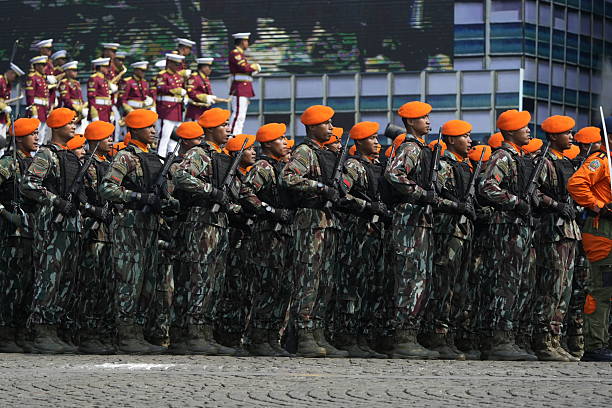 Jakarta, Indonesia -  October 5, 2025 : Indonesian National Armed Forces (TNI) personnel from various units participate in a military parade during the 80th anniversary celebration of the TNI at the National Monument (Monas) in Jakarta. Soldiers stand in formation with rifles while a military marching band performs during the official ceremony.