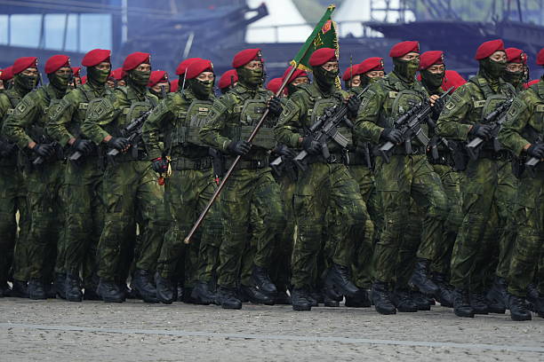 Jakarta, Indonesia -  October 5, 2025 : Indonesian National Armed Forces (TNI) personnel from various units participate in a military parade during the 80th anniversary celebration of the TNI at the National Monument (Monas) in Jakarta. Soldiers stand in formation with rifles while a military marching band performs during the official ceremony.