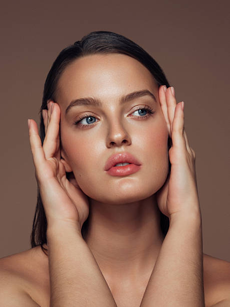 istock Portrait of a woman with hands framing her face in soft studio lighting setup 2262691610