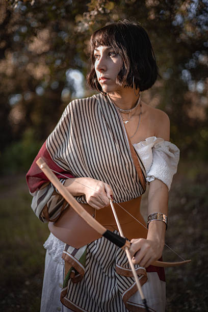 Confident woman with a bow, poised and ready in a natural setting
