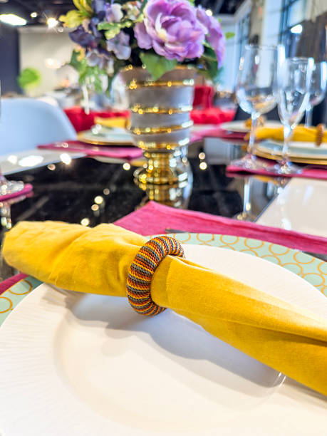 A close-up of an elegant dining table setup with a burgundy napkin wrapped with a gold band, a tea cup with a lid, and a delicate menu card. The table is set for a sophisticated event or fine dining experience.