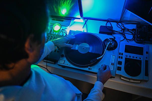 Person's hands manipulating a turntable and vinyl under neon lights