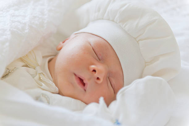 Peaceful baby lying on a bed and sleeping at home, close-up face portrait with closing eyes