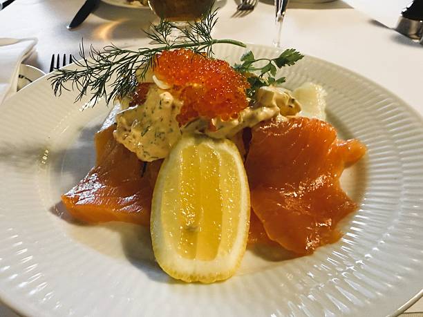 Refined assortment of traditional Danish smorrebrod topped with fresh salmon, halibut, luxurious caviar, creamy crab salad, and slices of lemon, beautifully presented in a stylish restaurant environment. Perfect for showcasing Nordic cuisine, gourmet dining, seafood delicacies, and elegant food presentation.