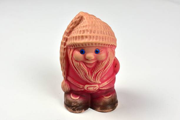 Vintage soviet pink gnome figurine with blue eyes and long beard isolated on white background. Cute retro rubber toy with textured hat and belt, studio shot, minimal composition, childhood character.