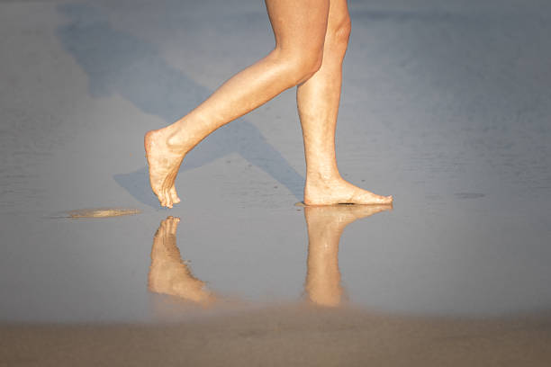 A girl barefoot walking on a rocky beach on a sunny day