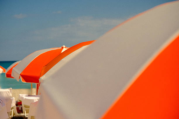 Orange and white umbrellas stand in the morning sun ready for beachgoers