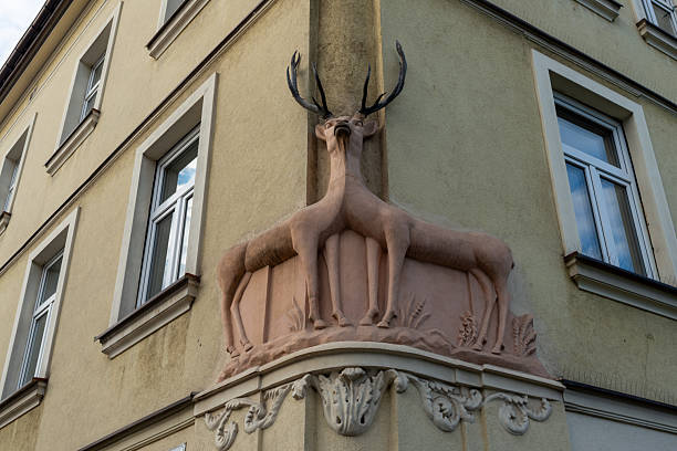 Krakow, Poland – May 11, 2025: Decorative deer sculpture with antler mounted on the corner of a historic tenement house. Architectural detail stands out against pastel facade and window of the old district.