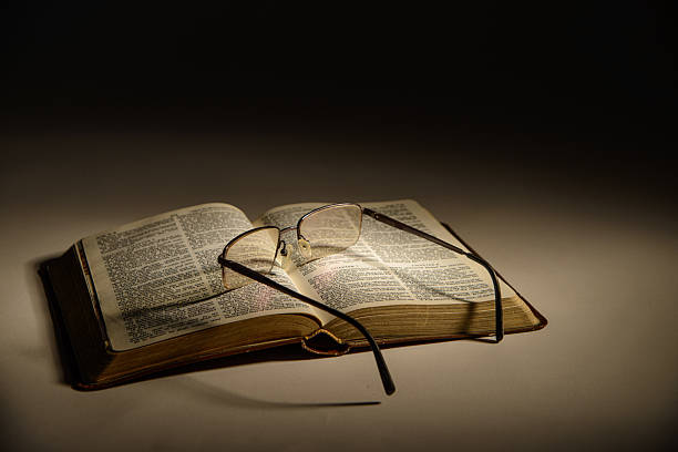 Glasses with black frame on top of the bible, small size and black bible letters