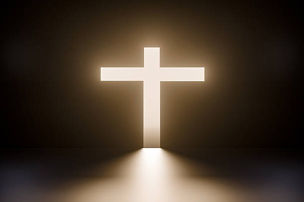 A glowing white Christian cross illuminating a dark space with warm divine light. Symbol of faith, hope, salvation, resurrection, and spiritual guidance. Conceptual religious background representing Christianity, Easter, belief, worship, and inner peace.