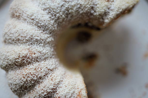 The dessert has a textured surface.  It appears dusted with powdered sugar.  The baked good is round.  The background is blurred
