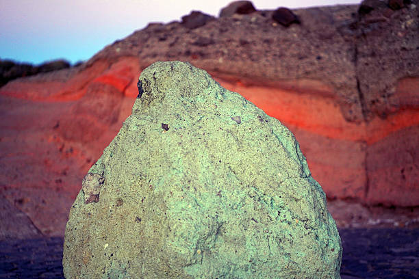 Texture of stone with colored red and green shades, fragments of different rocks of volcanic origin, lava formation close-up.