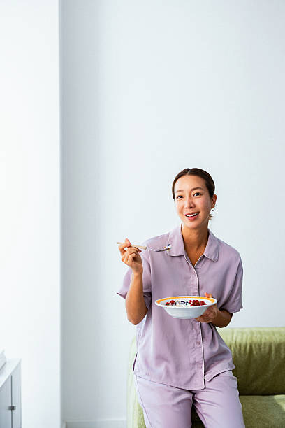 Woman Eating Breakfast Bowl At Home In Morning
