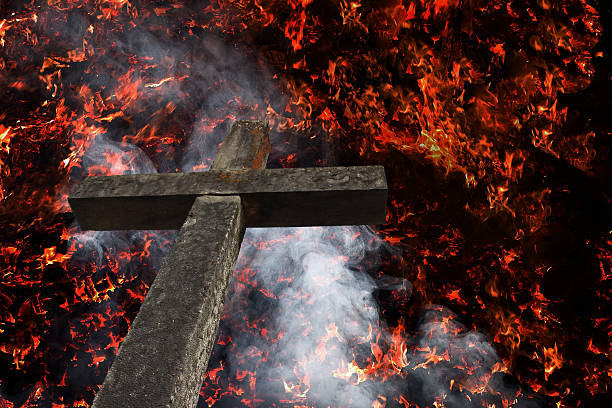 A stone cross is on fire. A stone cross with smoke in the fire
