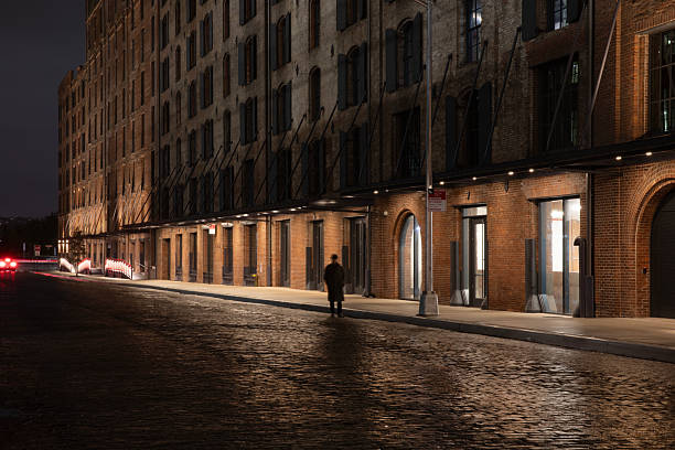 Person standing by the cobblestone street at night in Manhattan