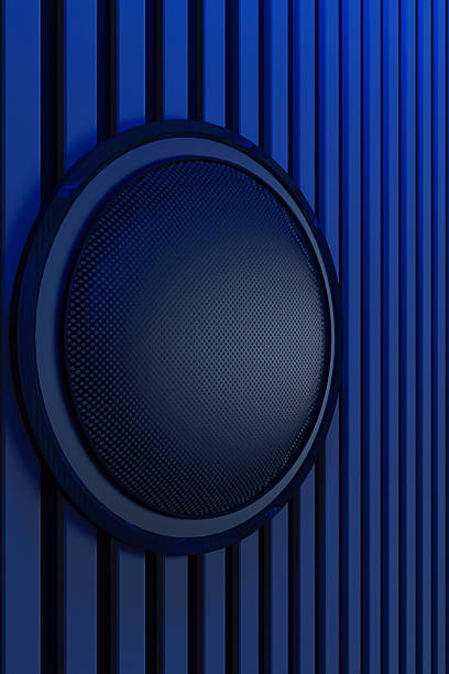 Modern wall speaker in home theater interior viewed from rear seating perspective. Foreground features a large, plush, tufted segmented sofa bed with pillows, completely bathed in deep blue ambient light. Dark polished tile flooring reflects the cool glow. The focal point is a massive blank black projection screen mounted on a wall featuring vertical acoustic slat paneling. A center channel speaker console sits directly below the screen. Intense blue LED strip lighting lines the ceiling coves and backlights the screen, creating a futuristic, monochromatic cool atmosphere. Symmetrical composition, architectural photography style, sleek minimalist design, cinematic lighting, high contrast.