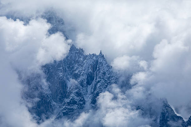 French Alpine mountain panoramic view with jagged peaks, glaciers and dramatic clouds in summertime