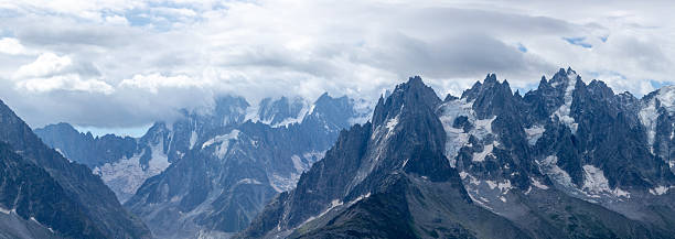French Alpine mountain panoramic view with jagged peaks, glaciers and dramatic clouds in summertime