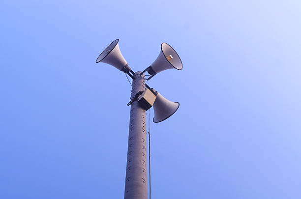 Three loudspeakers on tall pole against sky. Information dissemination concept.
