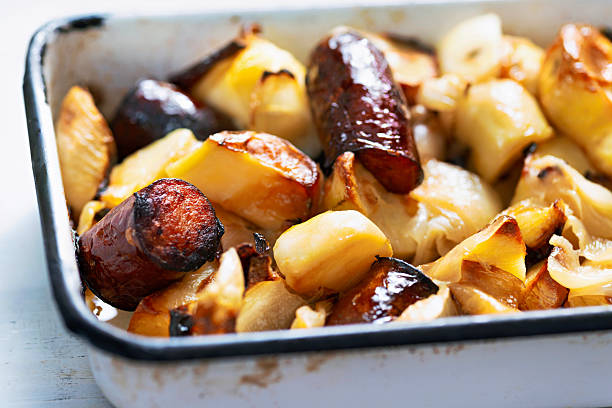 close up of a tray of baked sausages and potatoes