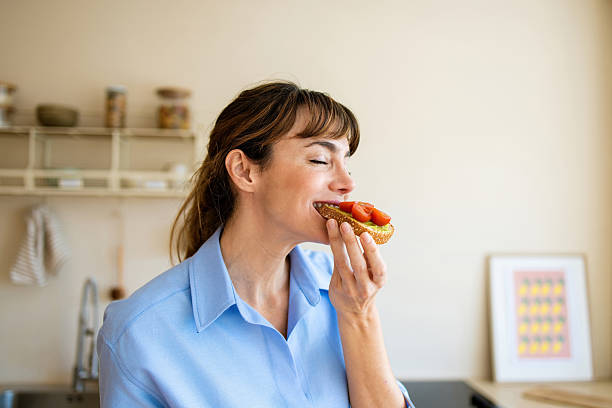 Woman enjoying healthy avocado toast with tomato for breakfast